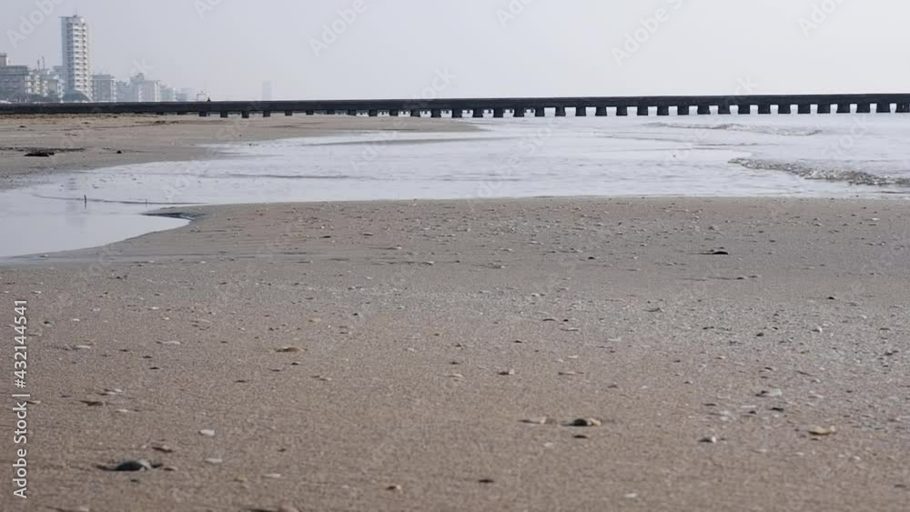 Passaggio con pontile, spiaggia estiva con secca e acqua che si sta ritirando sul mare 