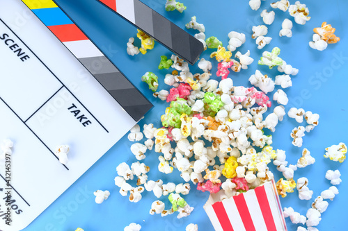 Movie clapper board and popcorn on blue background 