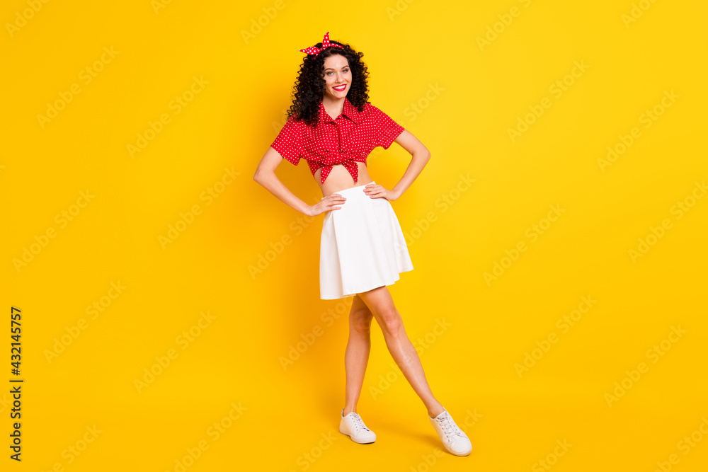 Full length photo of stunning charming young woman hold hands waist good mood isolated on yellow color background Full length photo of stunning charming young woman hold hands waist good mood isolated on yellow color background