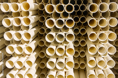 A stack of white electrical PVC conduit pipes in rows end on giving a repeat pattern of circles.