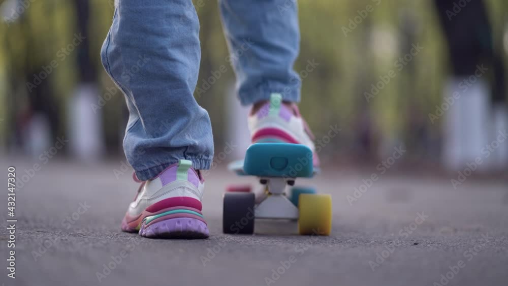 Close up legs riding on skateboard in motion of asphalt in park Close up legs riding on skateboard in motion of asphalt in park