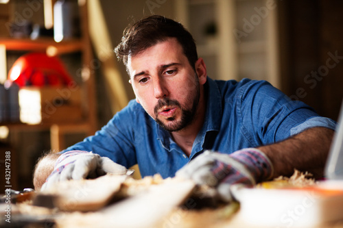 Handsome man working on wood craft. Young man working in workshop