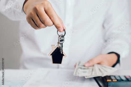 Estate agent hand holding house keys  with note bank. Mortgage concept. Real estate, moving home or renting property.