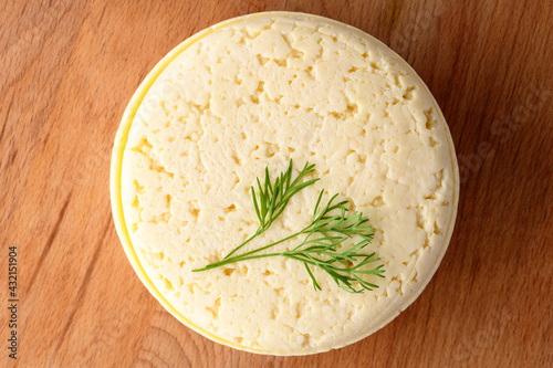 Cheese whole head with dill  on a wooden board. Homemade products photo