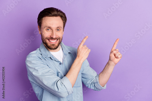 Photo of happy cheerful good mood young man point fingers copyspace promotion isolated on violet color background