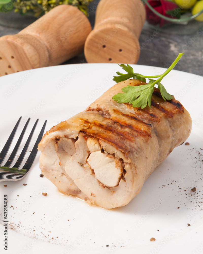grilled chicken roll decorated with greens on a white plate grilled chicken roll decorated with greens on a white plate