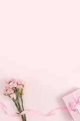 Mother's day background. Top view of gift with carnation bouquet on pink table background