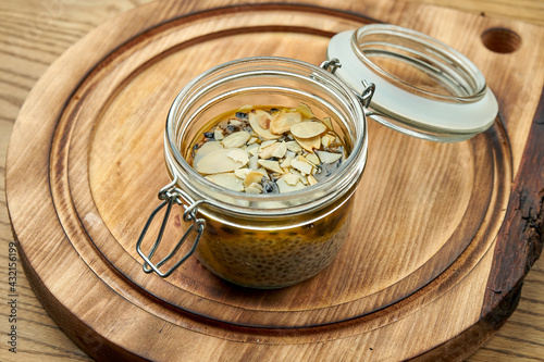 A healthy dessert is chia and passionfruit pudding with chunks of almonds in a glass jar. Takeaway food concept. Vegetarian sweets