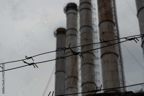 lines of barbed wire, pipes of a heat power station on the background

