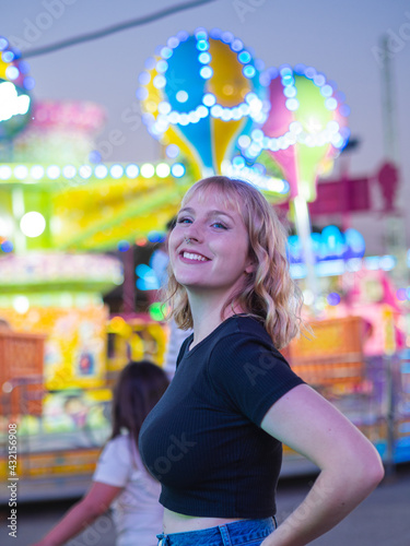 Mujer joven en una feria con atracciones y luces de fondo