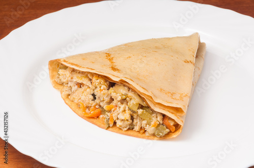 crepes with minced meat and vegetables on a white plate