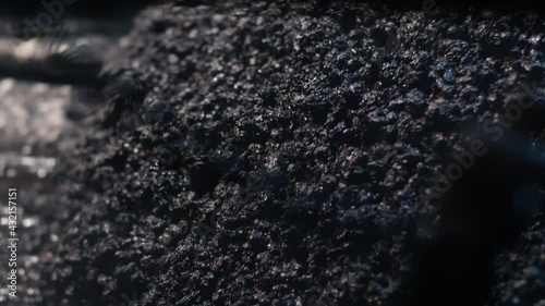 Close-up of fresh asphalt mix. An asphalt paver is laying asphalt mix on the road. Repair of roads at night, construction of new roads.