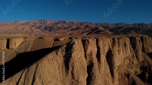 Man At Peak Of Red Cliffs In Remains Of Shahr-e Zuhak Fortress (Red City) In Bamyan, Afghanistan. - Aerial Drone Shot photo