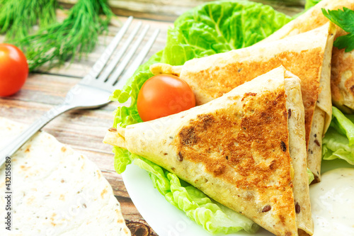 Fried homemade fast food, in close-up on a wooden board with herbs and a fork, tortilla