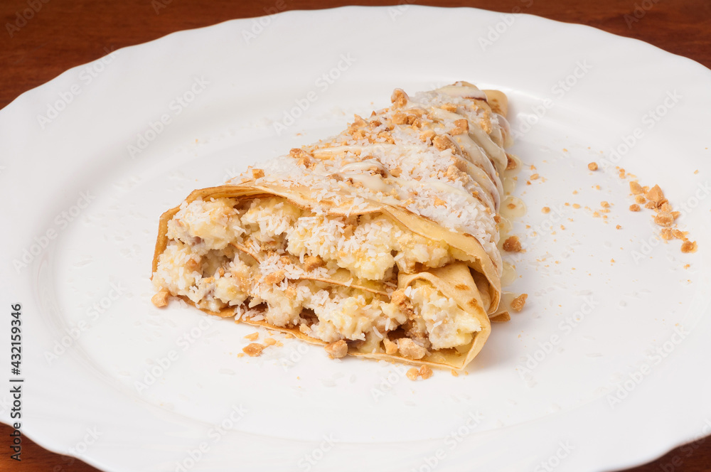 crepe with banana and coconut shavings on a white plate