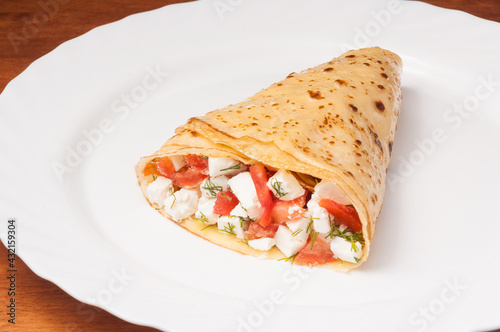 crepe with tomatoes and cheese on a white plate