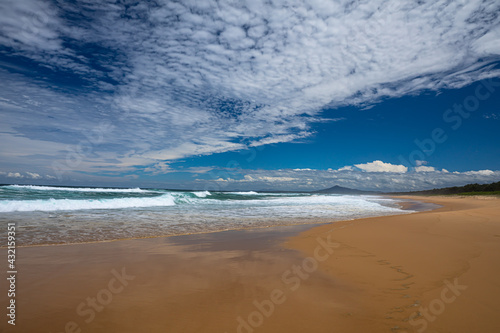A beautiful beach scene on a natural unspoilt beach on the east coast of Australia taken on a perfect day with deep blue sky and interesting cloud patterns overhead.