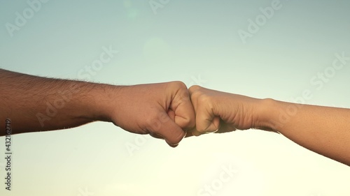 Male and female fists against the sky, trust, harmony, friendship. A fist to a fist is a sign, expresses consent, a gesture of respect. Teamwork concept. Lifestyle business team hands fists close up. © zoteva87
