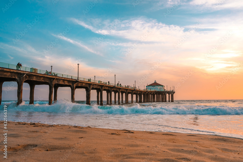 Manhattan beach pier at sunset, orange-pink sky with bright colors, beautiful landscape with ocean and sand
