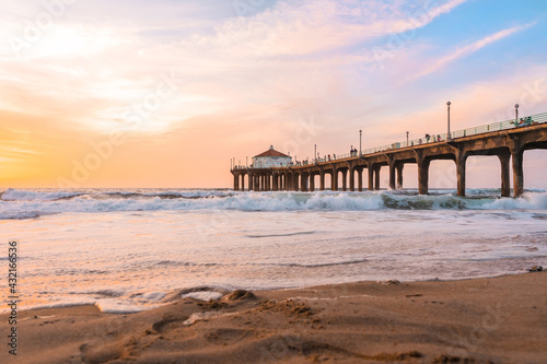 Manhattan beach pier at sunset, orange-pink sky with bright colors, beautiful landscape with ocean and sand