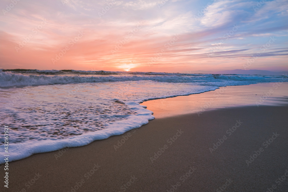 Beach in front of the ocean during sunset, calm ocean and beautiful colorful sky, California