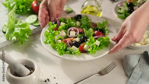 Vegetarian and organic food concept. Greek salad of fresh cucumber, tomato, lettuce, red onion, feta cheese and olives with olive oil. 