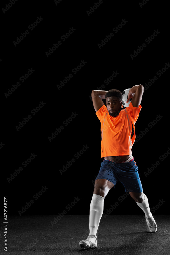 One African-american football player playing isolated on black background. Concept of sport.