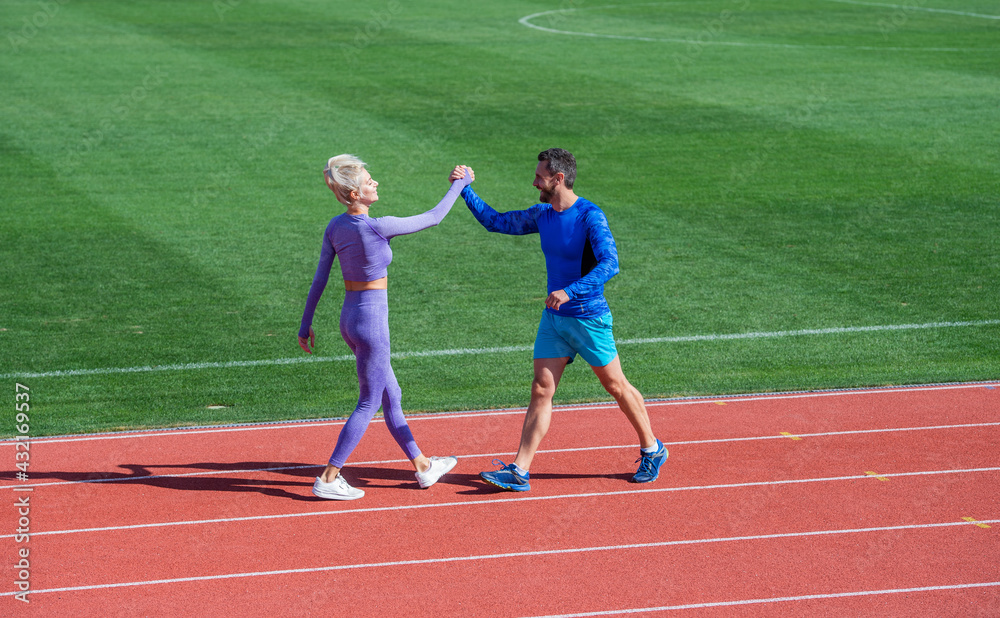 sport couple fitness partners celebrate team win with gesture of shake hand after exercising or compete in armwrestling on stadium running track arena outdoor, sport success