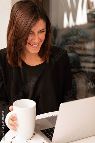 vertical image with a young woman working at home using laptop smiling in a meeting