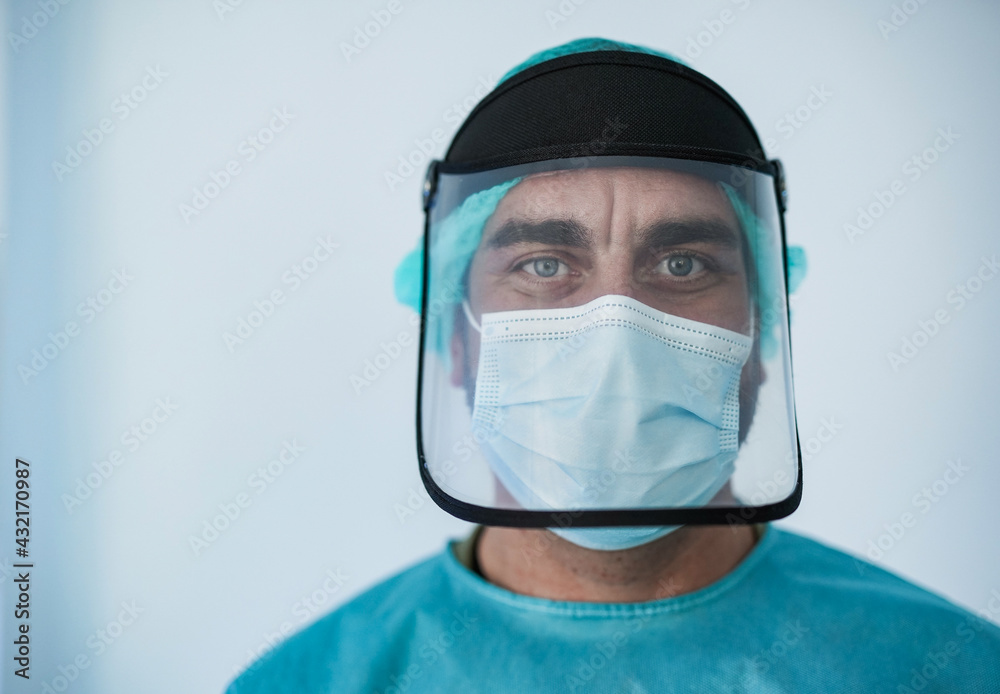 Portrait of caucasian male doctor with hazmat suit and safety mask - Mature man working inside hospital with safety measures for coronavirus outbreak