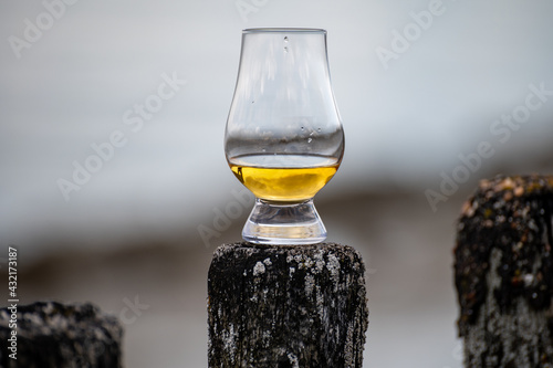 Photography Tasting of dram single malt scotch whisky on seashore in Scotland, old wooden po