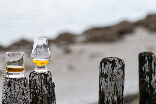 Obraz na płótnie Tasting of dram single malt scotch whisky on seashore in Scotland, old wooden po
