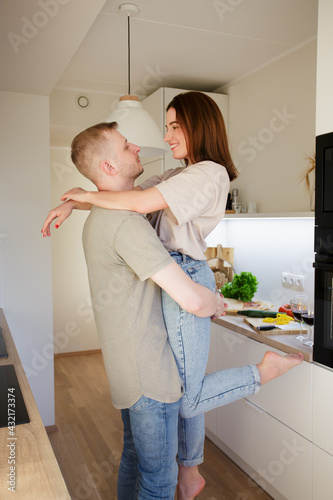 love, dating and relationship concept - portrait of young couple cooking and having fun in modern kitchen