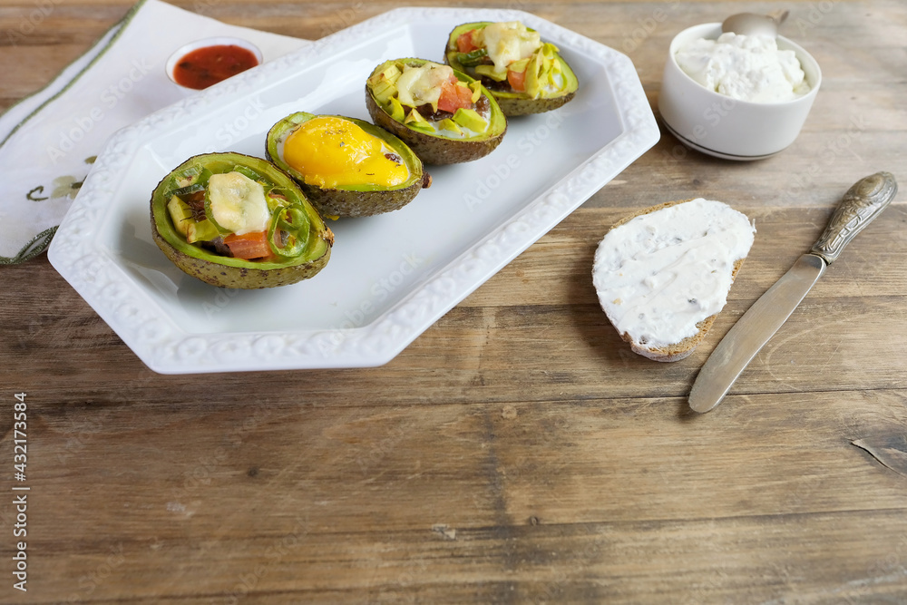 baked avocado stuffed with egg, vegetables, lie on a white dish, bread smeared with curd mass, linen napkin with embroidery, concept of post-holiday detox, diet, healthy food baked avocado stuffed with egg, vegetables, lie on a white dish, bread smeared with curd mass, linen napkin with embroidery, concept of post-holiday detox, diet, healthy food