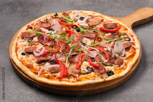 pizza with bacon and hunting sausages on a gray background
