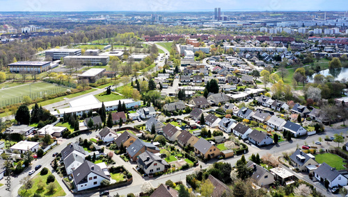 Aerial view of a housing estate on the outskirts of the city of Wolfsburg in Germany with a school in the background and factories on the horizon.