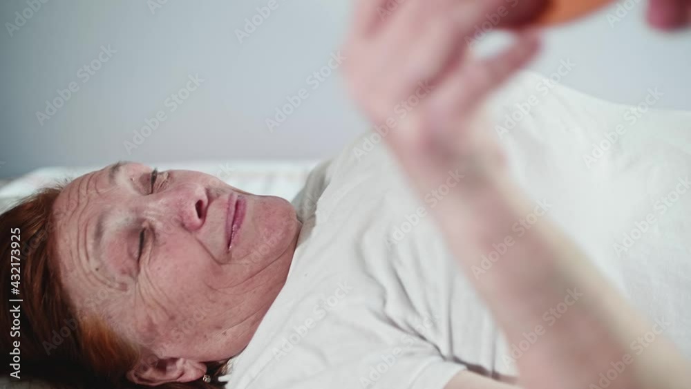 Old woman lying on bed passes Mishin coil to another person.. This person covers up camera with coil. Alternative medecine. Old woman lying on bed passes Mishin coil to another person.. This person covers up camera with coil. Alternative medecine.