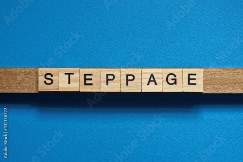 gray word steppage in small square wooden letters with black font on a blue background photo