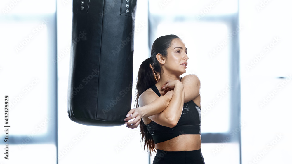 young sports woman stretching near punching bag.