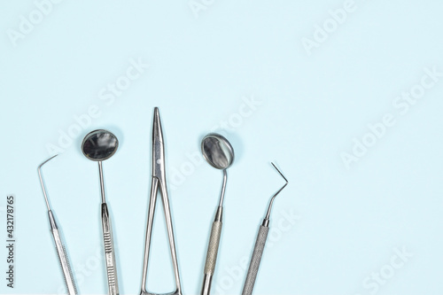 Medical dental instruments on light blue background with copy space. Flat lay close up top view on dental equipment. dental mirrors, probes, forcepts