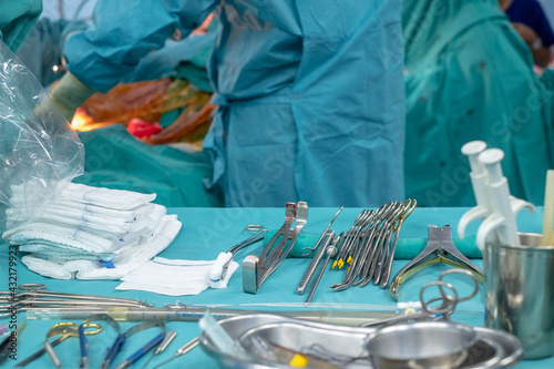 Medical team performing operation. Close up of scrub nurse taking medical instruments for operation. Medical and instrumentalist nurse working in an operating room with scissors of surgery.