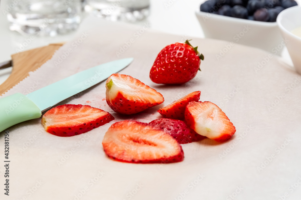 Chef's knife and slices of strawberries on a cutting board. Baking paper. Healthy food concept. High quality photo