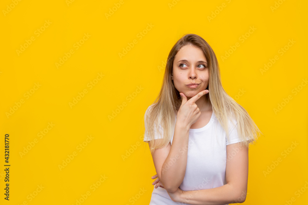 A young caucasian pretty thoughtful blonde woman in a white t-shirt imagines, thinks looking up at empty copy space for ads promo offer quote text slogan isolated on a bright color yellow background A young caucasian pretty thoughtful blonde woman in a white t-shirt imagines, thinks looking up at empty copy space for ads promo offer quote text slogan isolated on a bright color yellow background