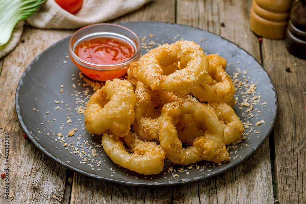 Rings of squid in batter with chili sauce on old wooden table Rings of squid in batter with chili sauce on old wooden table