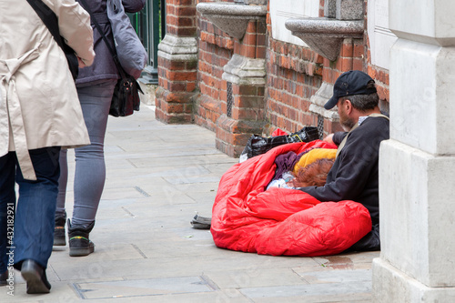 Couple of homeless, beggars lying on the ground against the passing by people.A man holds his woman head.Central London, Piccadily street. photo