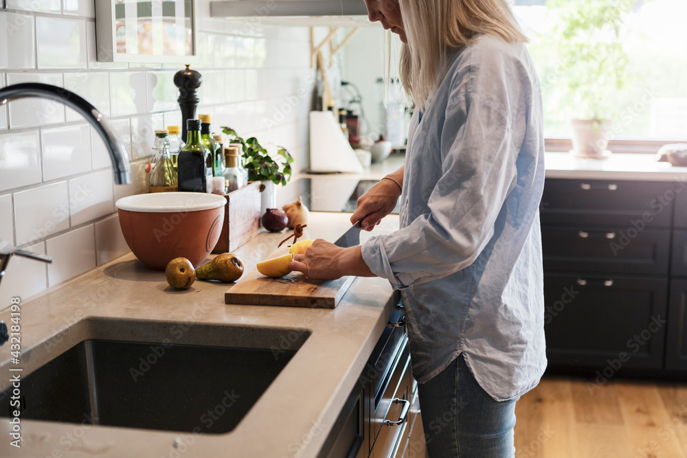 Mid adult woman cutting pear in kitchen Mid adult woman cutting pear in kitchen