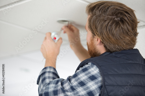 male electrician fixing light on the ceiling