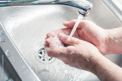 Male Washing Soaped Hands Under Water Stream At A Kitchen Sink