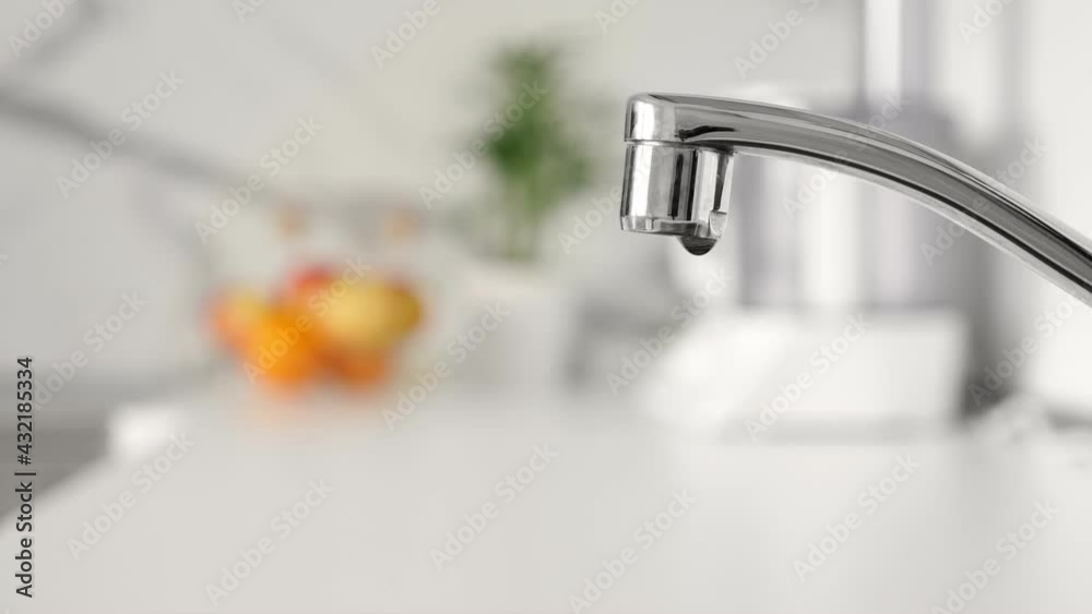 Water dripping from faucet tap at kitchen. Closeup