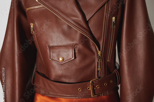Girl in a brown leather jacket with gold clasps and zippers. Stitched luxury jacket with pockets. Clothing background. Horizontal photo.